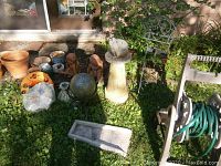 Photo showing terracotta cherub statues, assorted pots, mosaic glass globe light, and pedestal with frog sculpture.