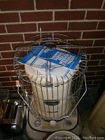 Photo of beige kerosene heater with metal cage and user manual.