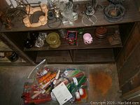 Wide view showing various candle holders on shelves and a large bin of assorted candles below.
