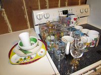 Full view of various character mugs, glass tumblers, and plates grouped together on kitchen counter