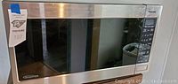 Close-up of Panasonic microwave showing stainless steel front, black glass door, and control panel.