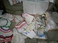 Photo of assorted needlepoint dollies and embroidered linens spread on a surface