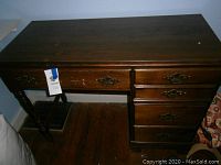 Image of dark stained wood desk showing front side with drawers and turned legs