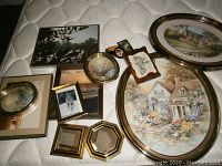 Overview of all framed artwork showing various shapes and sizes arranged on a mattress, highlighting gold frames and different art styles