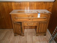 Full front view of wooden dresser showing two side cabinet doors open and rope style drawer handles.
