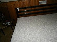 King size platform bed frame with black wood vertical slat headboard and white patterned mattress