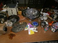 Overview of vintage small kitchen gadgets on wooden table including kitchen scale, metal strainers, graters, timers, and other tools.