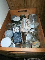 Wood crate filled with Ball glass jars, lids, small boxes and other glass containers