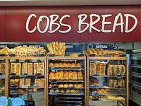 Photo of Cobs Bread storefront with various breads displayed on shelves.
