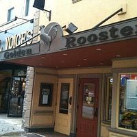 Exterior photo showing entrance sign of Golden Rooster delicatessen with the business name clearly visible on signage above the doorway.