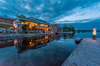 Evening view of Thousand Islands Playhouse venue on the waterfront with building and dock lights reflecting on the water.