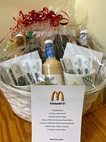Wicker basket wrapped in cellophane showing mugs, syrups, coffee bags, vouchers and book