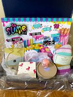 Photo showing the full gift basket contents including So Slime DIY kit, Umbra pineapple picture holder, reading socks, EOS lip balm, and Unicorn Magic box.