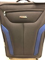 Front view of WestJet Concorde suitcase showing black body with blue accents and front zippered pocket, with metal logo plaque.