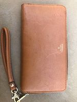 Front view of the camel color leather clutch with Fossil logo embossed in white lettering.