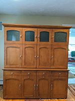 Closed front view of wooden office organizer bureau showing upper and lower cabinets with doors and drawers.