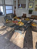 Overview of metal mesh dining table and six matching chairs with decorative place settings in sunroom.