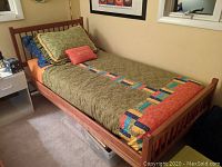 Wooden twin bed frame with reddish brown finish, slatted headboard and footboard, birdseye view showing bedding and pillows (no mattress included)