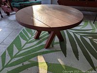 Side angle of the round coffee table showing the wooden planks and angled legs.