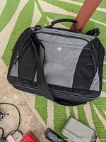 Black and gray laptop briefcase sitting on a green and white striped rug.