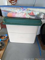 Large plastic bin with lid and clear lid container holding rolled wrapping papers and other wrapping materials