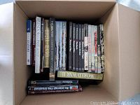 Image showing 18 books and book sets tightly packed in a single open cardboard box. Majority are hardcover, some paperback. Titles relate mostly to history and fiction.
