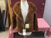 Front view of the vintage brown mink fur jacket displayed on a mannequin.