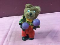 Front view of the vintage bear wind-up toy holding maracas, showing the face, shirt, and pants.
