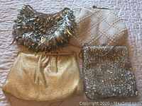 Four vintage ladies purses arranged on a light surface showing beaded, sequin, and metallic designs
