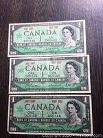 Front of three 1967 Canadian Centennial One Dollar Bills showing Queen Elizabeth II and series details.