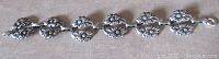 Full view of the 7.5 inch long silver flower link bracelet showing the 6 flower embossed links and clasp.