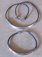 Set of sterling silver and black rubber cord necklace and bracelet laid flat showing overall design and clasps.