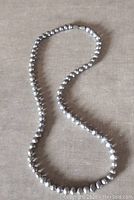 Full view of the purple-blue Keshi cultured pearl necklace displayed on a flat surface showing the entirety of the strand