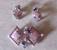 Front view of the brooch/pendant and the two clip earrings showing pink art glass cabochons and rhinestone settings.
