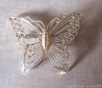 Front view of the butterfly brooch showing detailed filigree design and gilt finish.