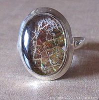 Front view of oval ammolite stone in sterling silver setting showing distinctive mosaic pattern and polished bezel.