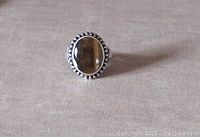 Full view of the vintage sterling silver ring with oval tiger's eye stone on a fabric background.