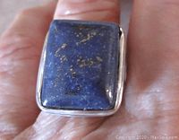 Top-down view highlighting the rectangular lapis lazuli stone with visible gold pyrite inclusions and silver tone bezel setting on a size 8 band.