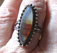 Front close-up showing marquise agate with natural banding and beaded silver frame.