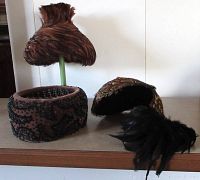Three vintage 1940s hats including two feather-covered hats and one beaded fabric hat base. Feathers are brown and darker, beaded hat detailed with intricate black beadwork on brown fabric.
