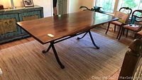 Full view of rectangular hardwood dining table with iron base in a room setting
