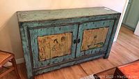 Front view of buffet showing distressed aqua finish and Asian-themed painted panels on doors