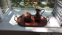 Full view of copper tray holding the pitcher and ice bucket on a windowsill showing overall condition and setting.