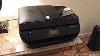 Front and top view of the black HP OfficeJet 4650 printer placed on a table.