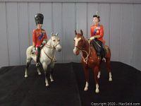 Group shot of both porcelain figurines on black cloth with gray panel backdrop