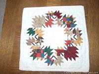 Full view of the tabletop showing the maple leaf quilt pattern on a white background.