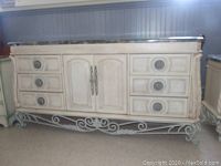 Front view of Pulaski dresser showing six drawers and center cabinet with carved details and wrought iron legs.