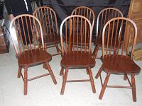 Wide view of all six pine Windsor back chairs arranged together showing dark finish and condition.