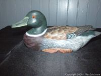 Side view of the wooden duck decoy showing detailed painting and orange eye.