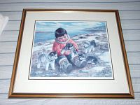 Framed print titled "Best of Friends" depicting a young Inuit child with husky puppies, signed and numbered by Nori Peter.